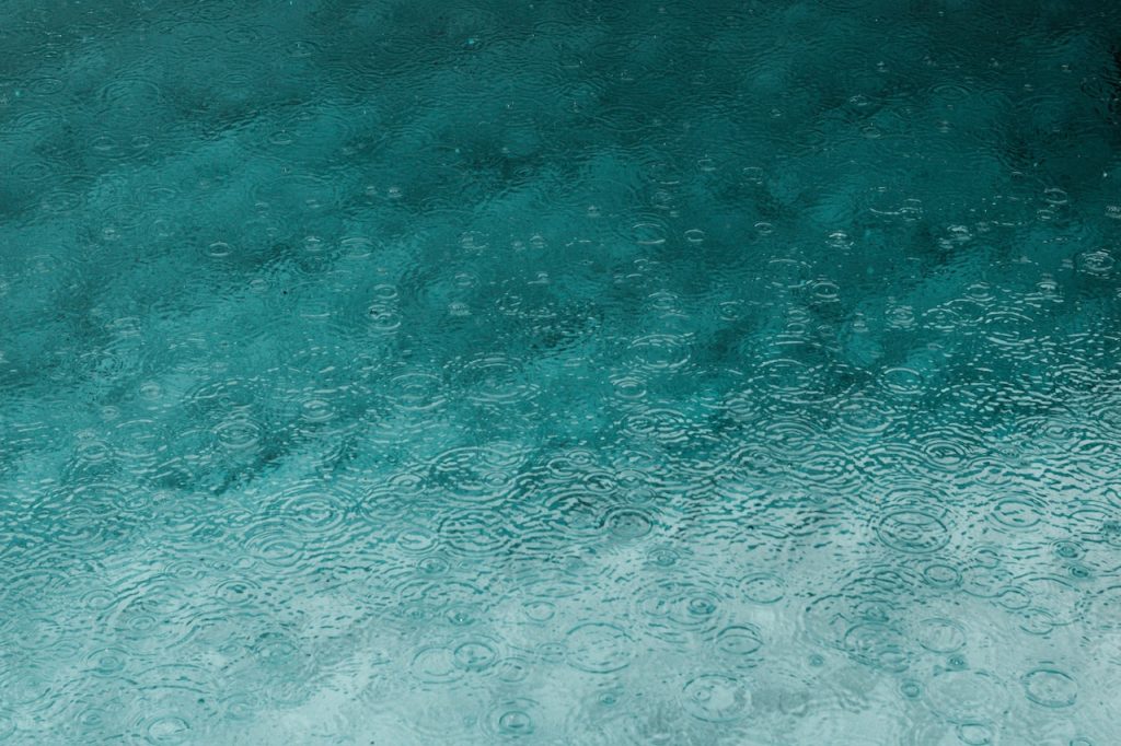 Gotas de lluvia cayendo sobre el mar, dibujando ondas en patrones.